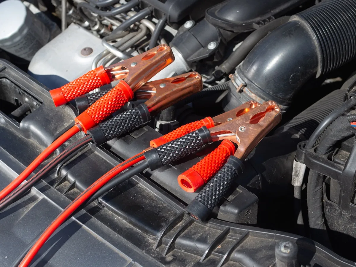 Battery terminals and jump leads connected under a car bonnet